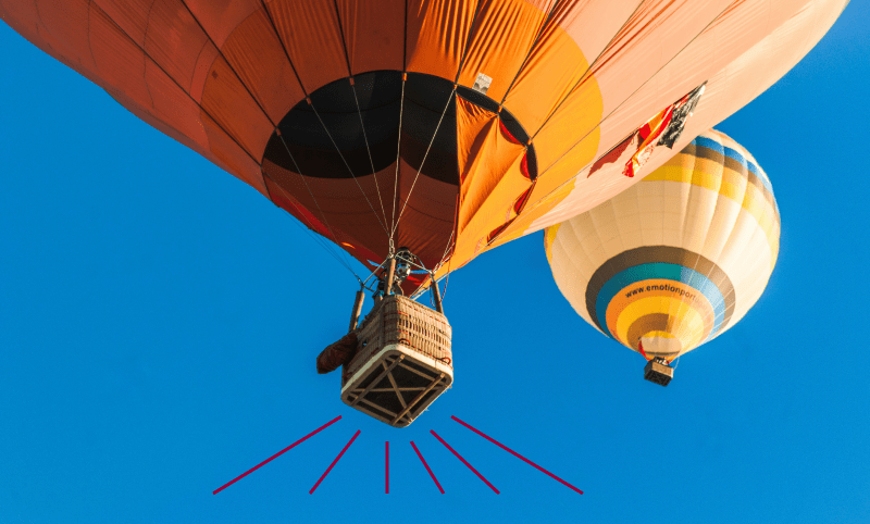 Photo of two hot air balloons against a blue sky